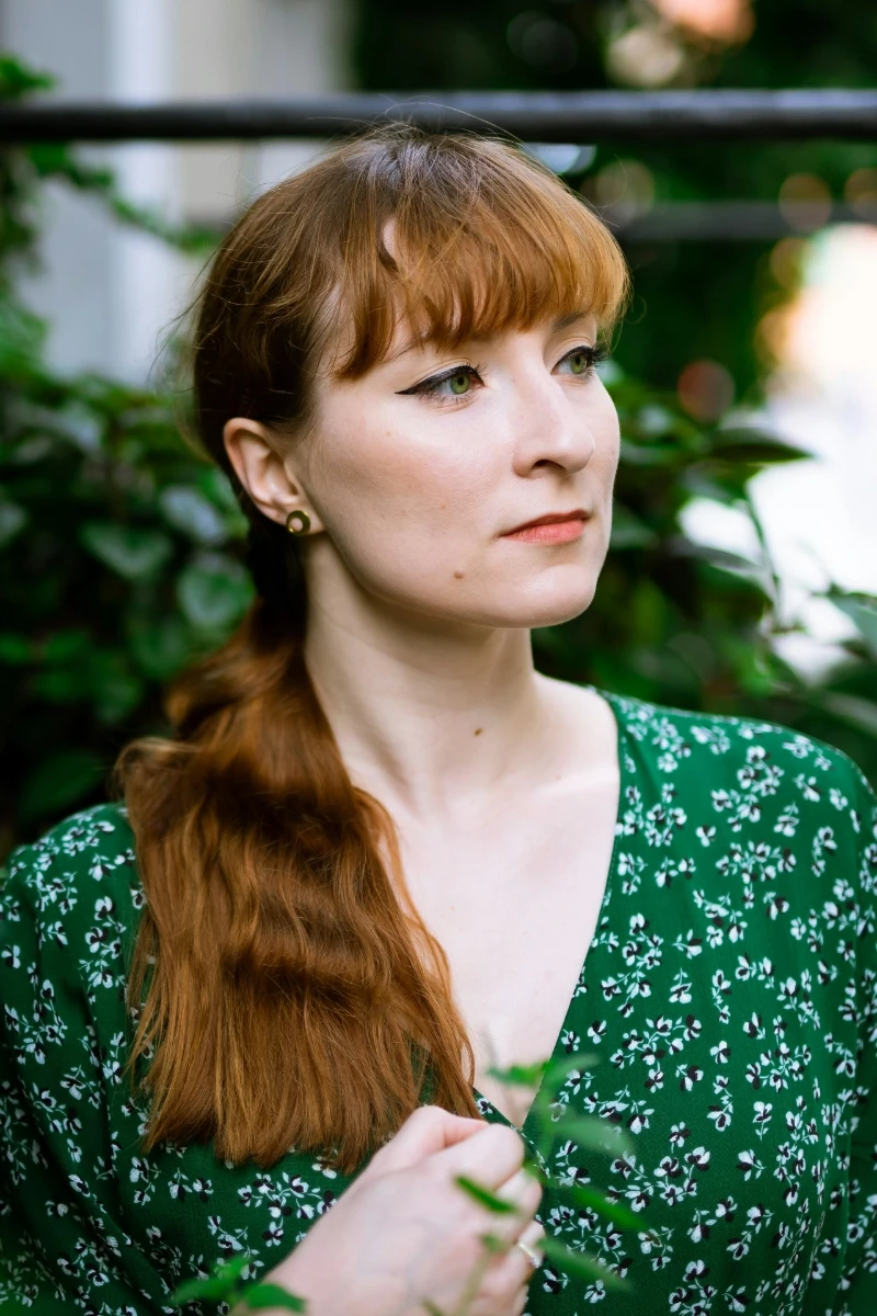 a man in a black hoodie standing in front of a tree