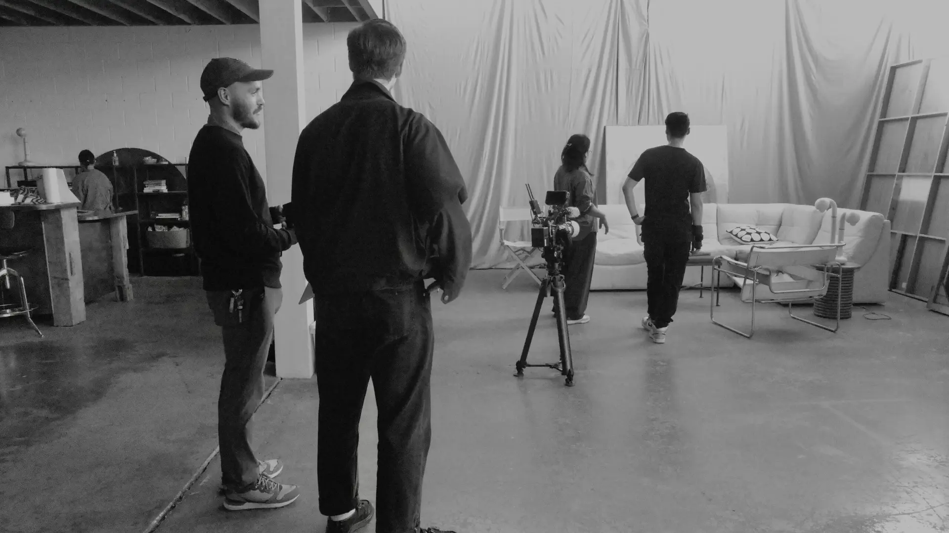 Black and white photo of two people looking at a computer screen with papers on wall