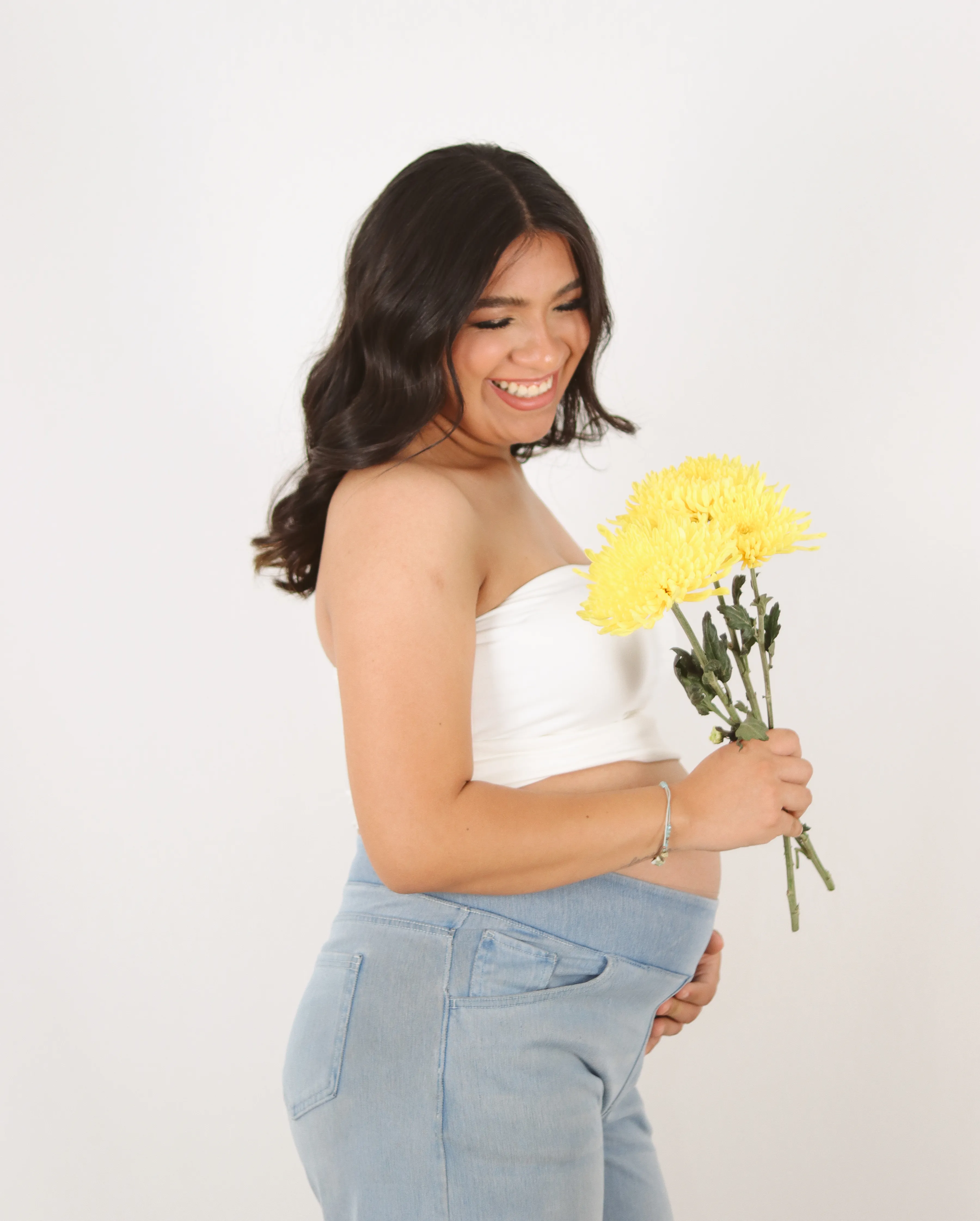 Mujer embarazada sonriendo con flores amarillas