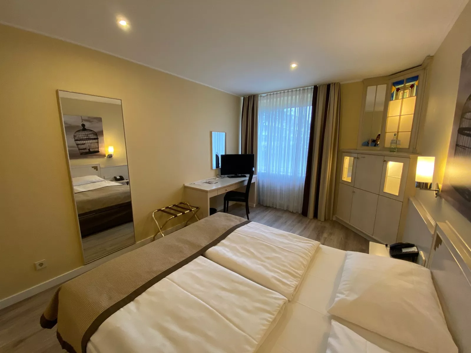 Standard Zimmer vom Bett aus fotografiert mit Blick auf einen Spiegel, TV und einem Sideboard