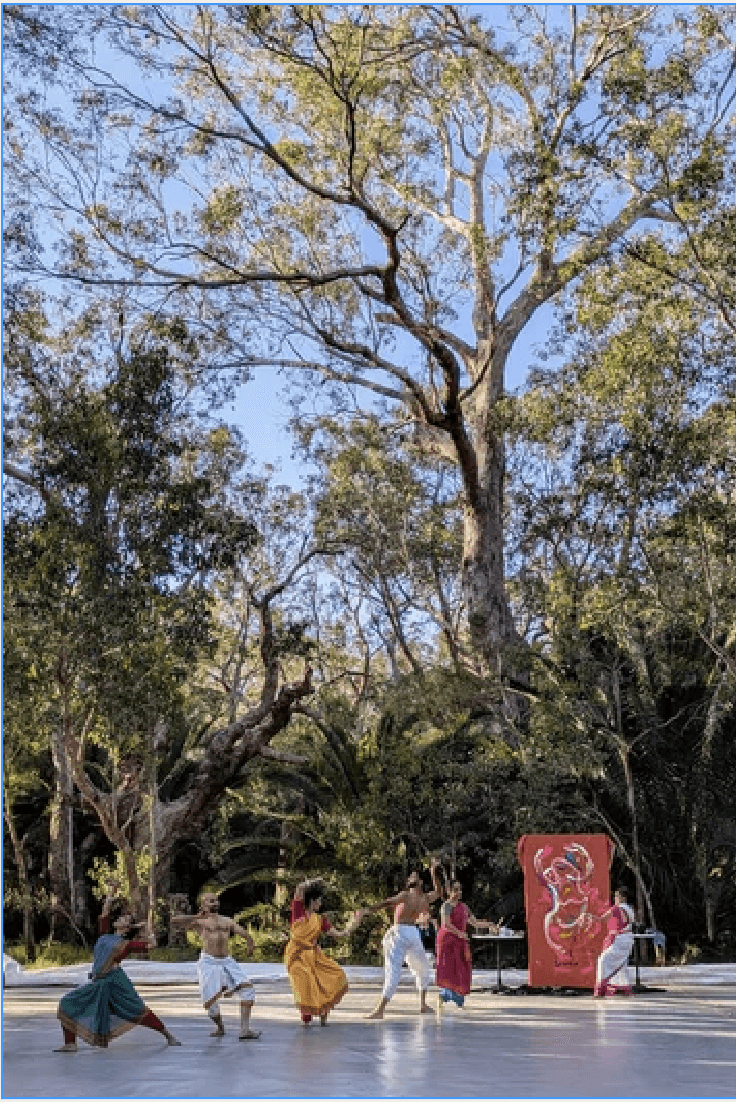 A person with shoulder-length blonde hair wearing a black newsboy cap and a black sweater.