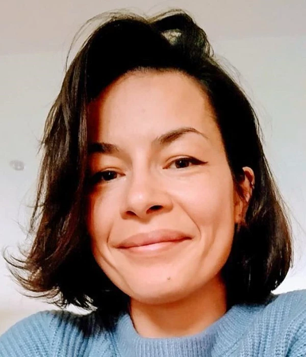 Photo of Alice Durand who has a bob cut wearing a blue jumper while smiling at the camera