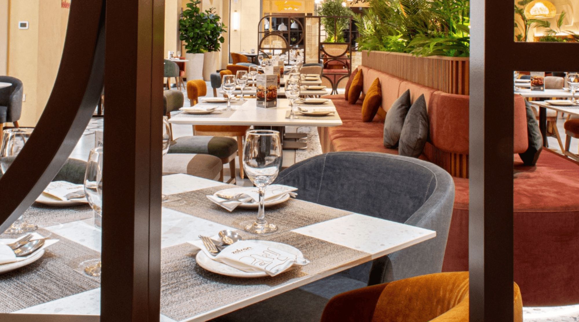 Zafran Indian Kitchen with modern seating and table setups using red, grey, and maroon colors.