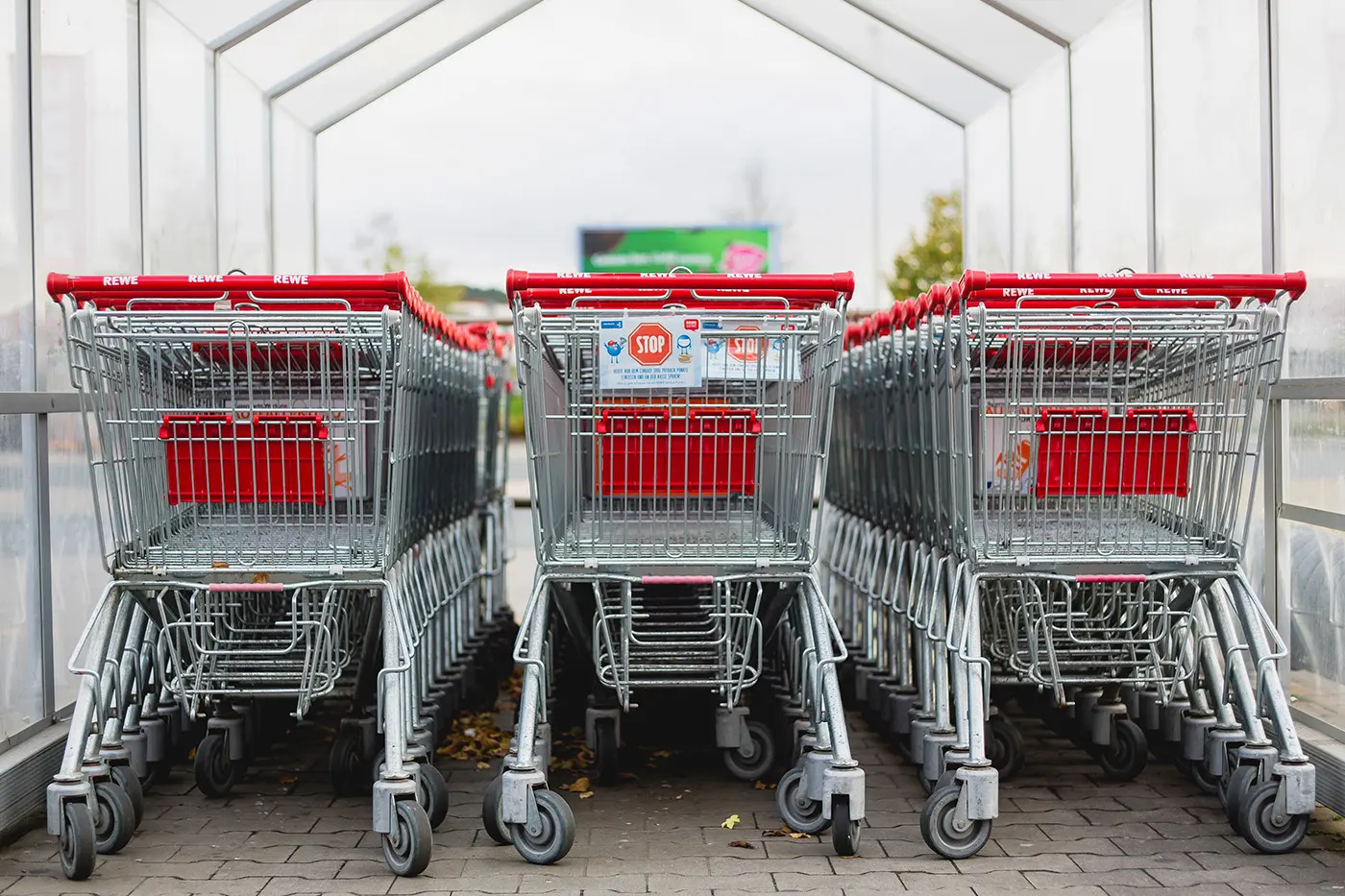 Rad av röda och silverfärgade kundvagnar på en parkeringsplats vid ett köpcentrum