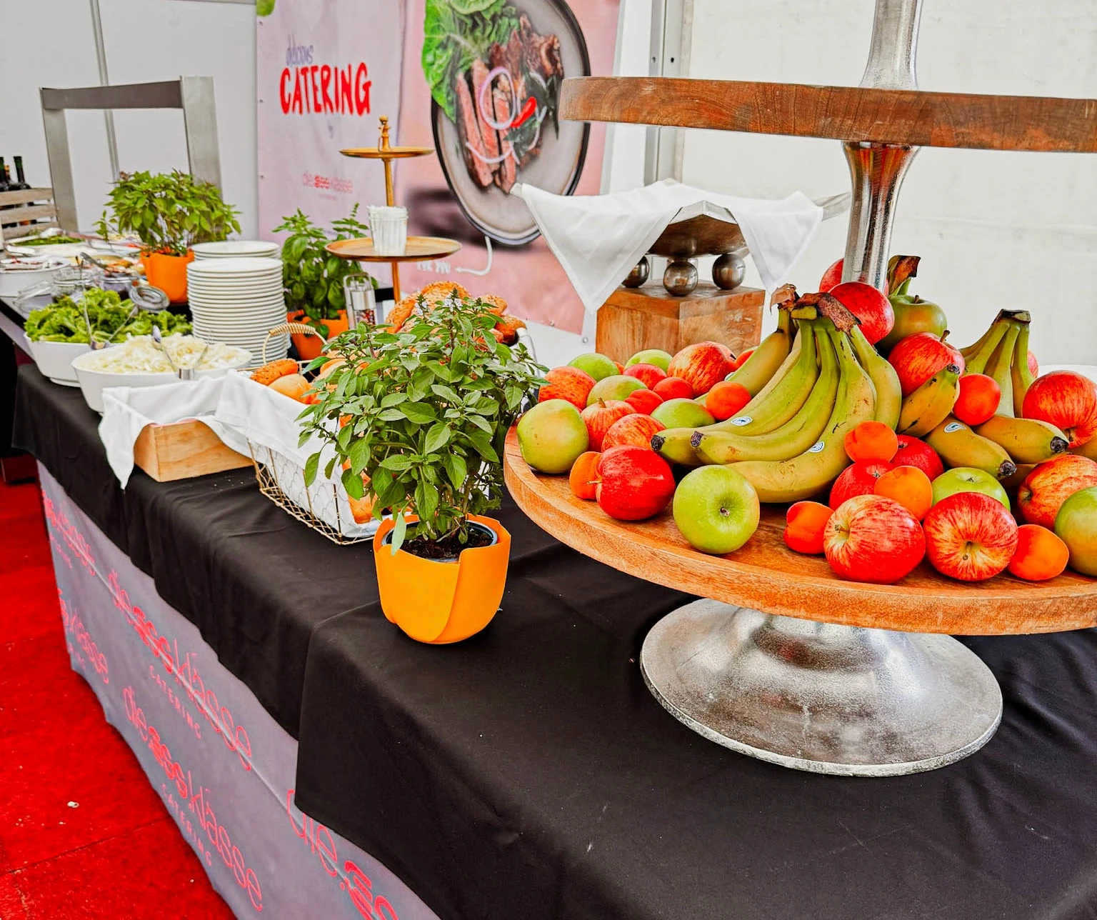 A vibrant table setting featuring burgers, hot dogs, fries, and colorful drinks, illuminated by string lights.