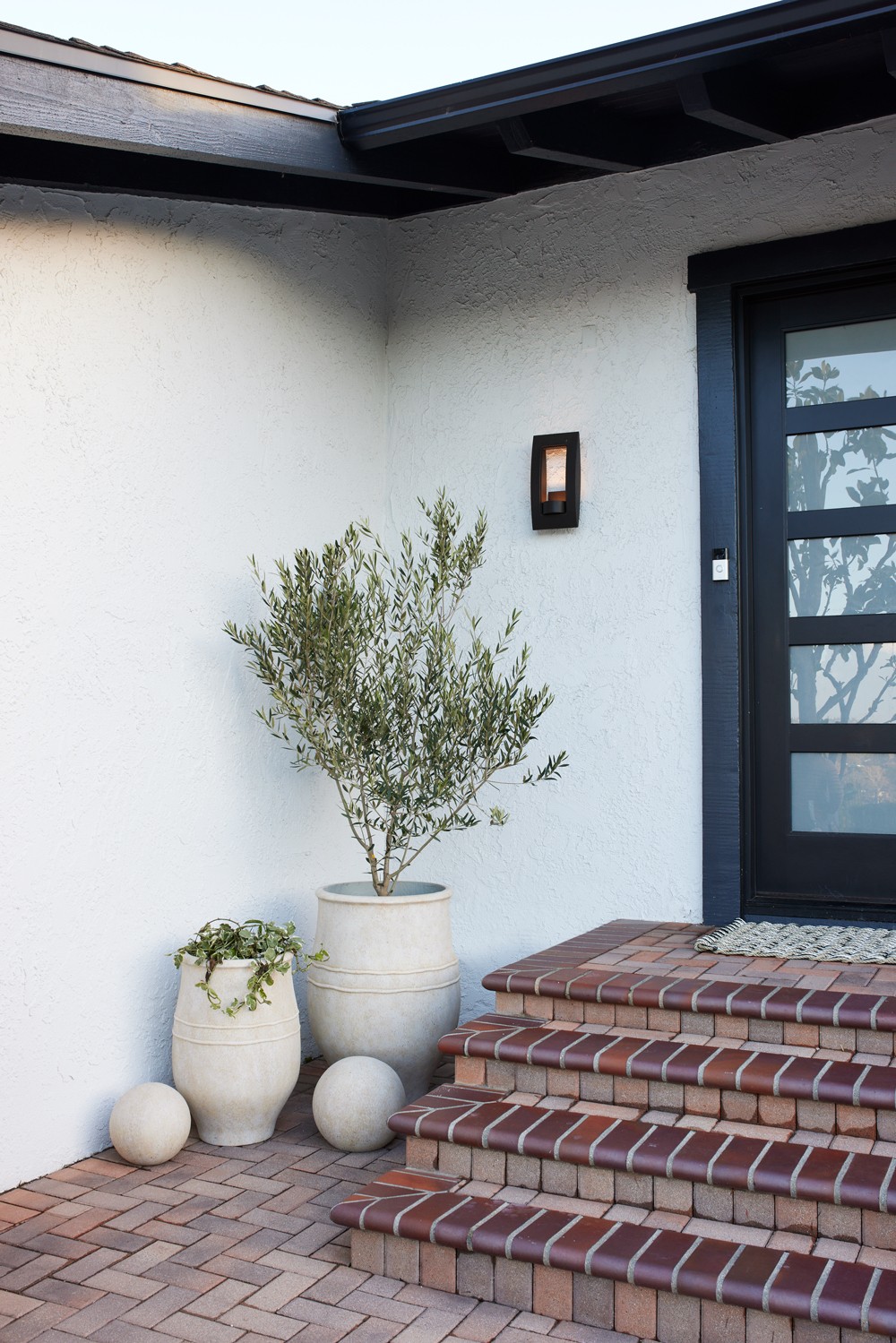 Stacked brick staircase ascending to an elegant glass door entry