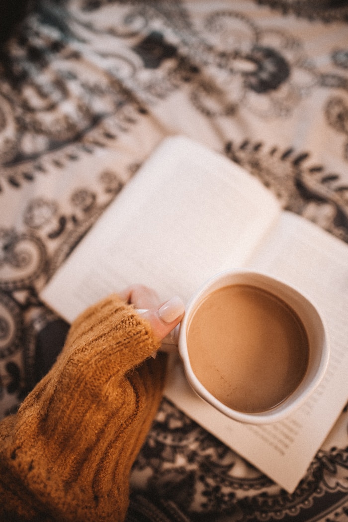 Person holding a warm drink while reading