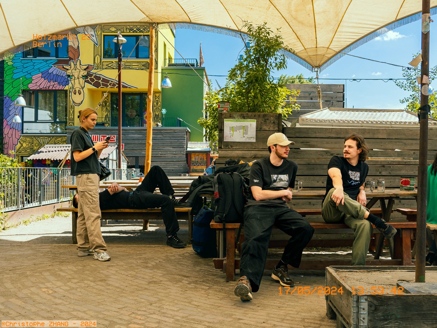 Scène de vie à Holzmarkt Berlin avec des amis assis près de bâtiments artistiques.