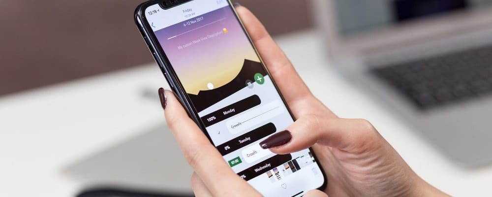 Person using a smartphone app with a calendar and mountain sunset background.
