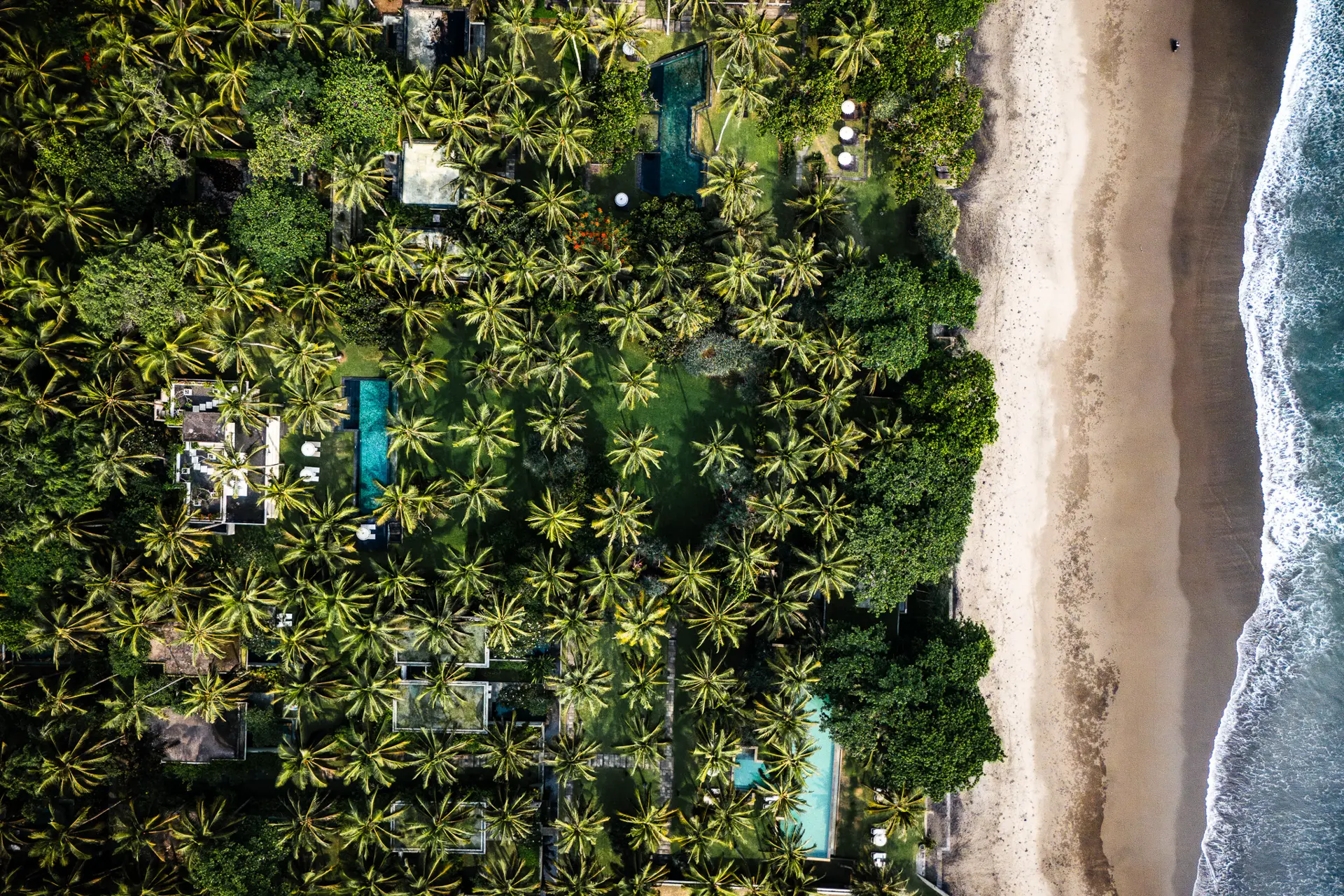 Luftaufnahme eines Luxus-Resorts an der Küste von Bali – Kelapa Retreat & Spa umgeben von Palmen und Sandstrand