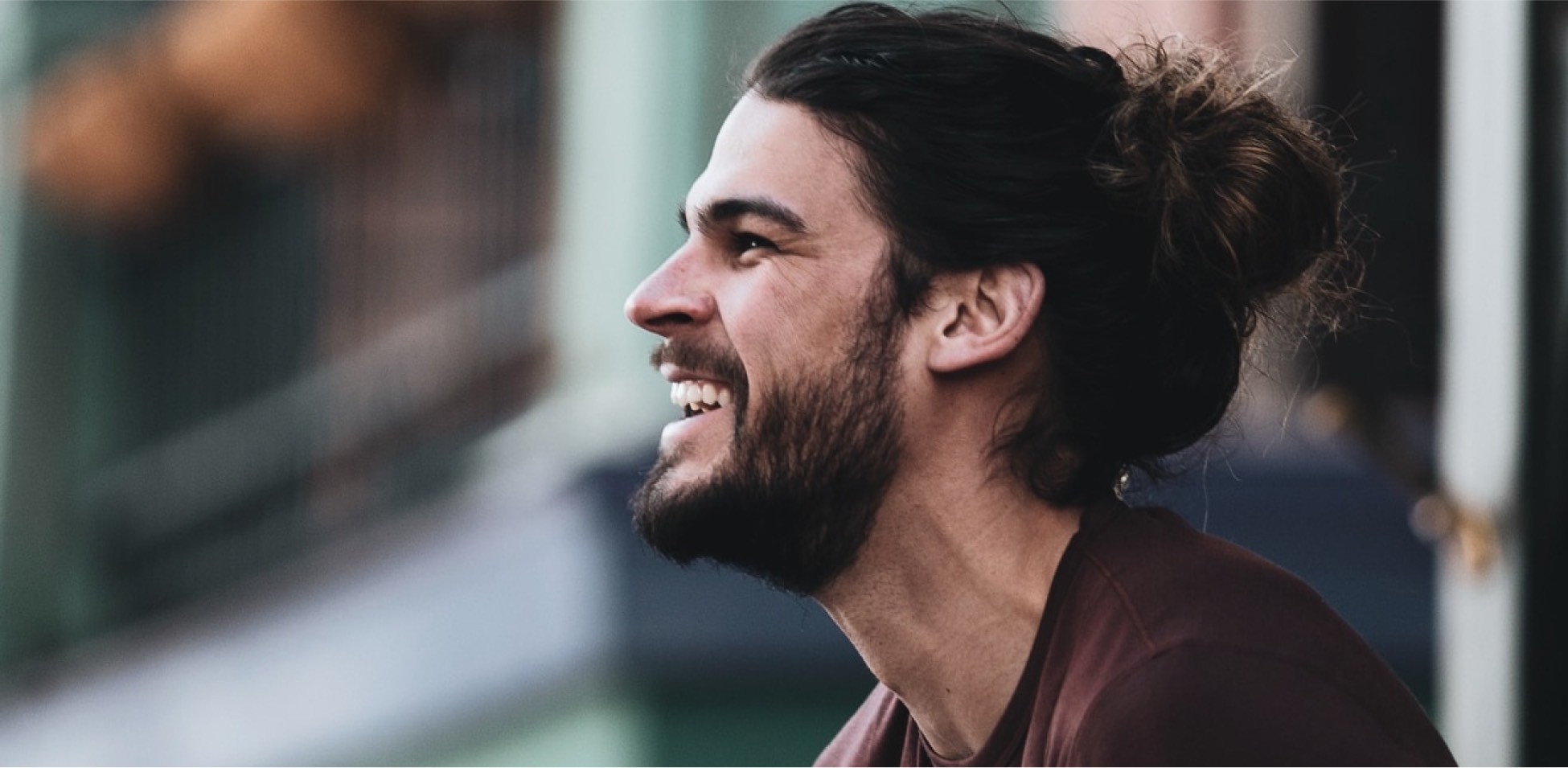 A person with long hair wearing a beard smiling and holding something.