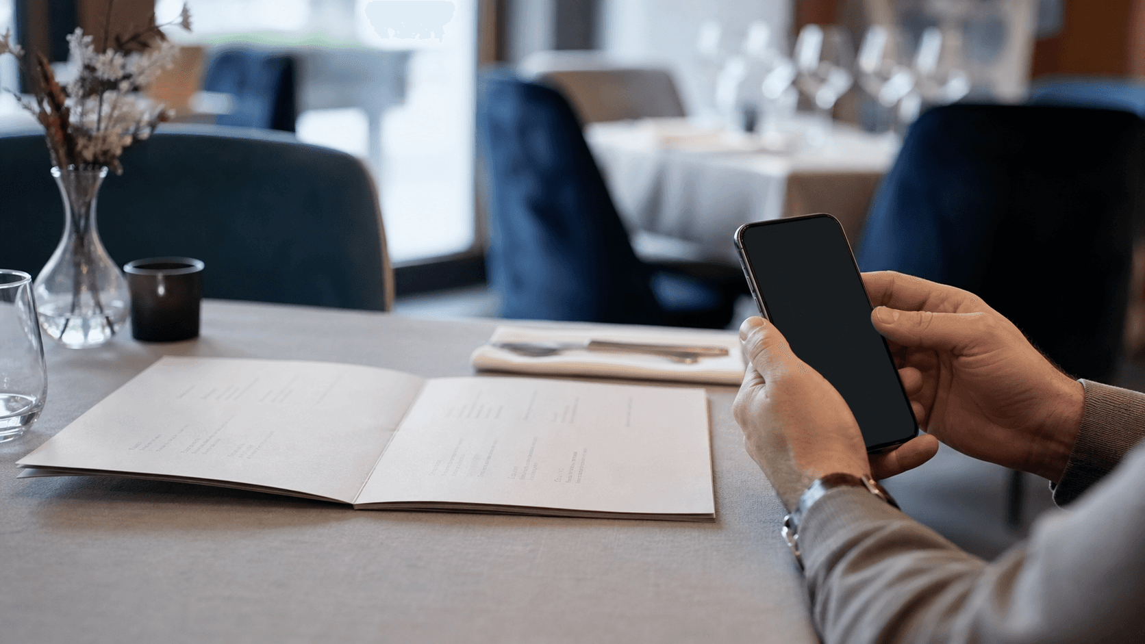 Convive consulte une carte de restaurant et un téléphone éteint, menu en ligne.