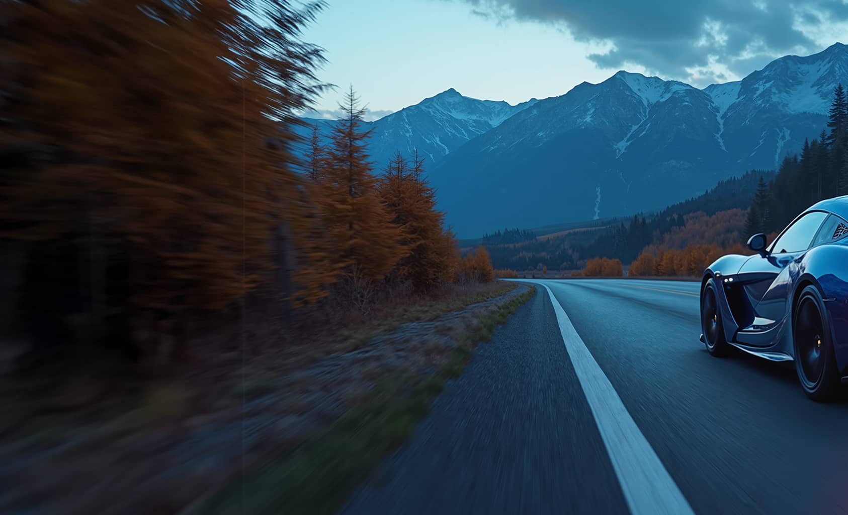 Une voiture de sport bleue roulant à vive allure sur une route de montagne au crépuscule, avec des arbres d'automne et des sommets enneigés en arrière-plan.