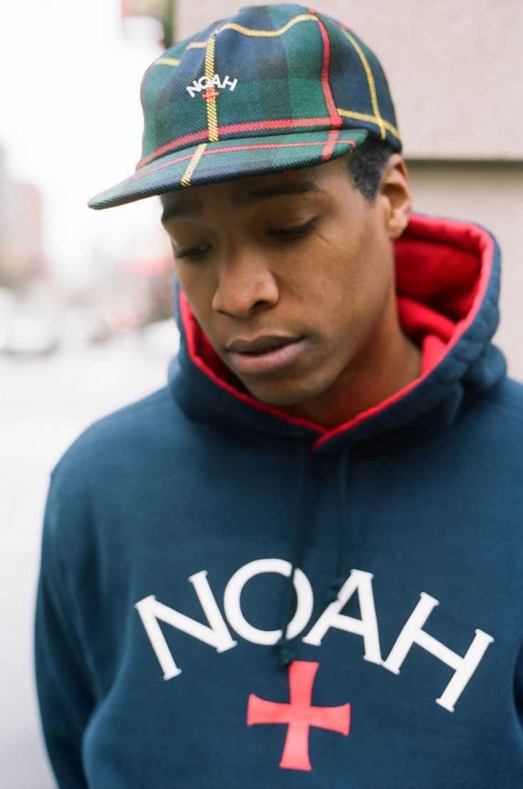 a man wears a noah hat and hoodie showing their iconic logo