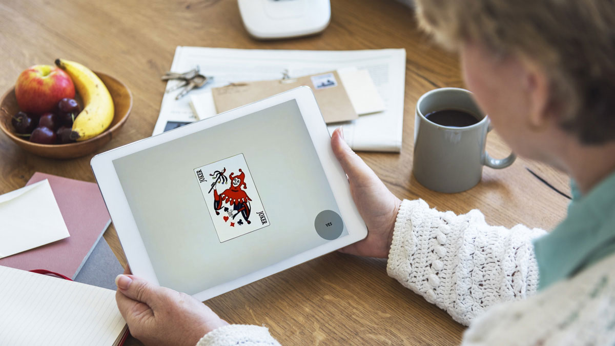 Elder sitting at kitchen table taking a cognitive assessment on a tablet