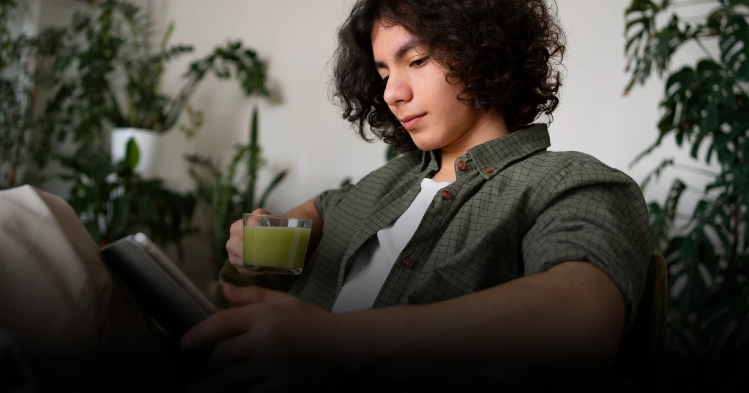 Homem sentado em um sofá enquanto toma um chá e faz sua sessão de psicologia online