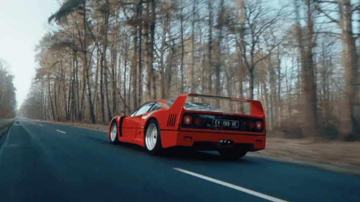 A vintage ferrari driving down a forest road