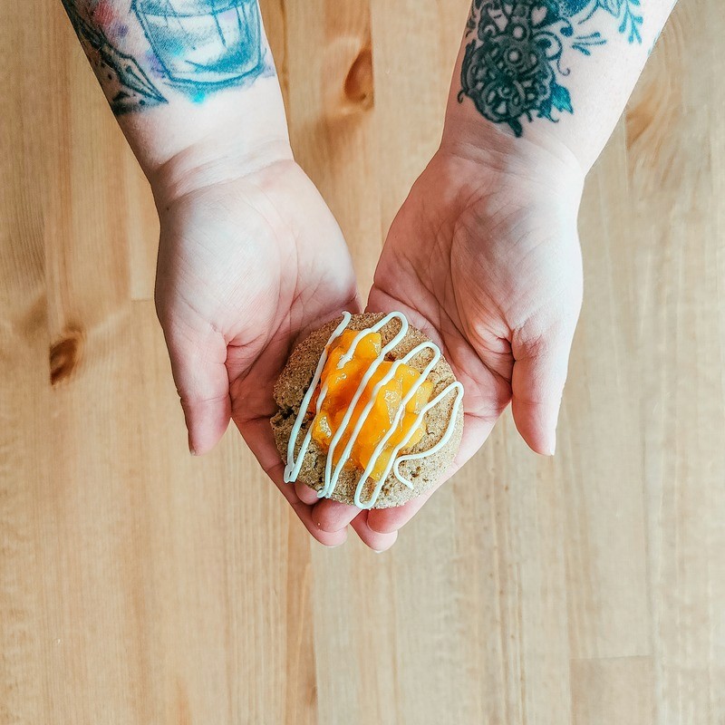 Cookie being held with two hands, featuring a peach cobbler filling