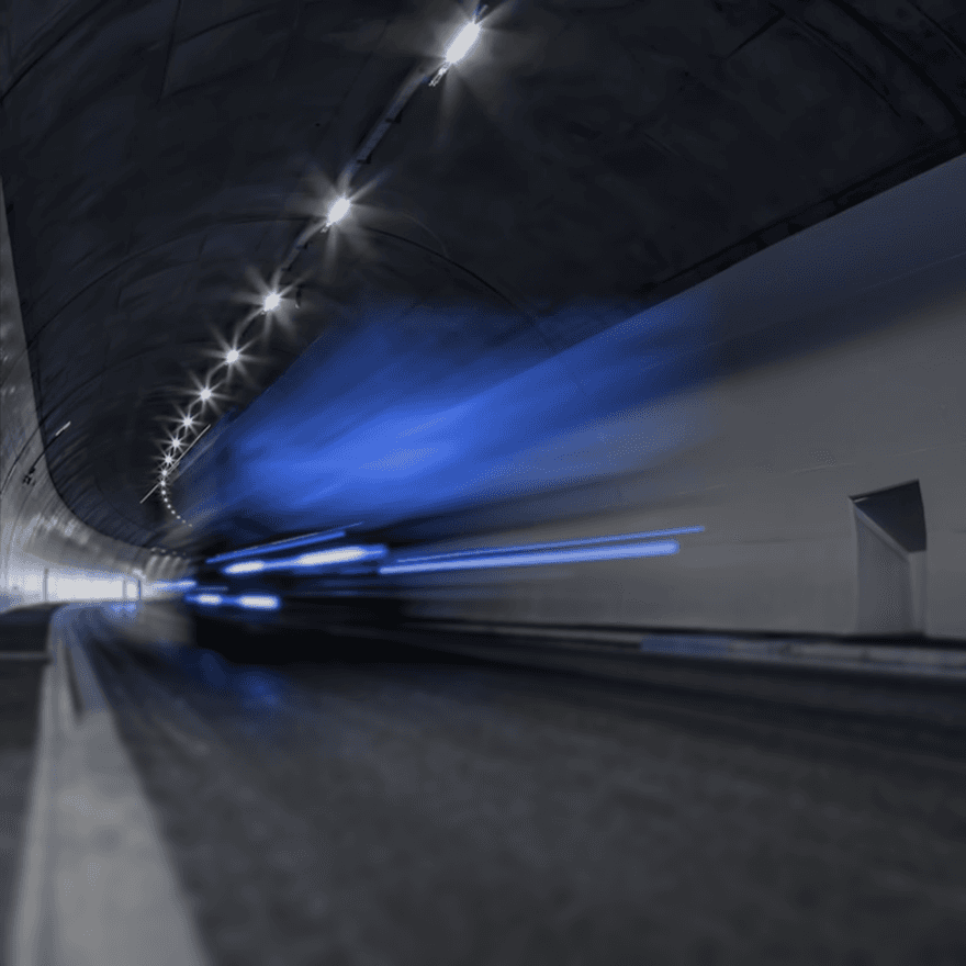 A dimly lit tunnel with blue and white lights, showcasing motion blur from a moving vehicle.