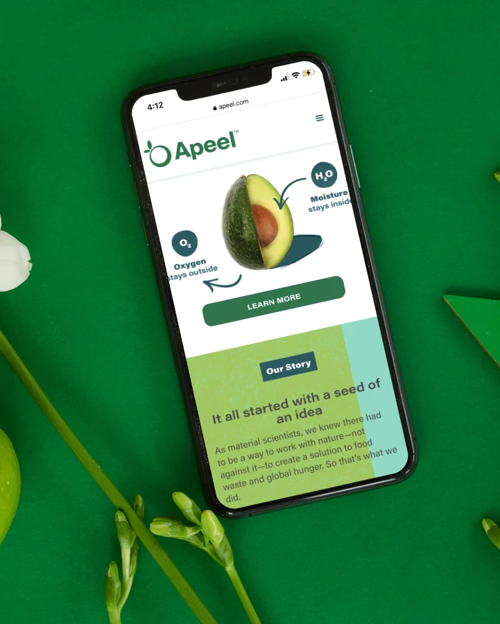 A smartphone on a green surface displaying the Apeel website, explaining the technology behind the extended shelf life of treated produce.