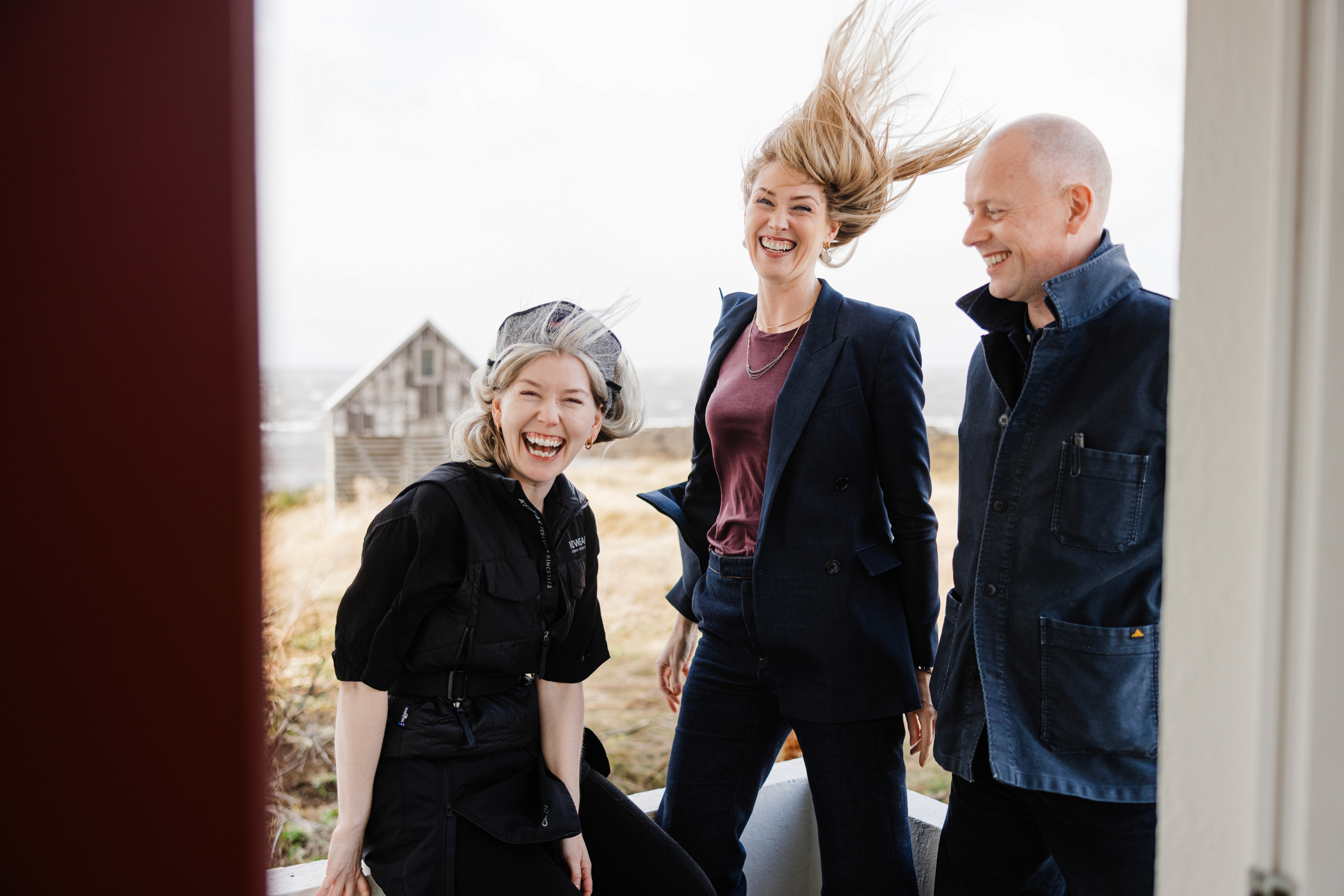 Artist Ásta Fanney Sigurðardóttir with Pocket Universe curators Margrét Áskelsdóttir and Unnar Örn, laughing together in the wind on the Icelandic coast.