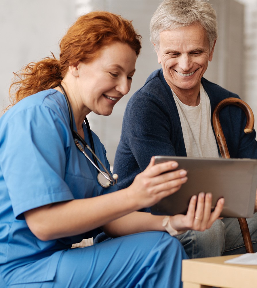 Nurse showing a tablet to a smiling senior patient