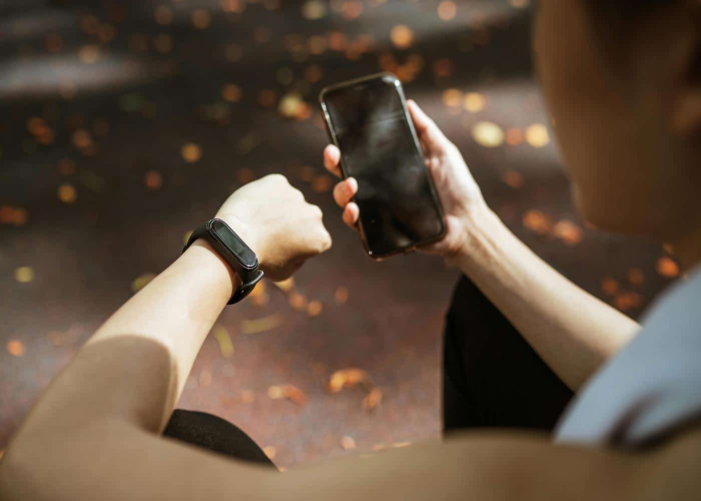 Woman wearing a fitness tracker and using a phone to track her essential health metrics
