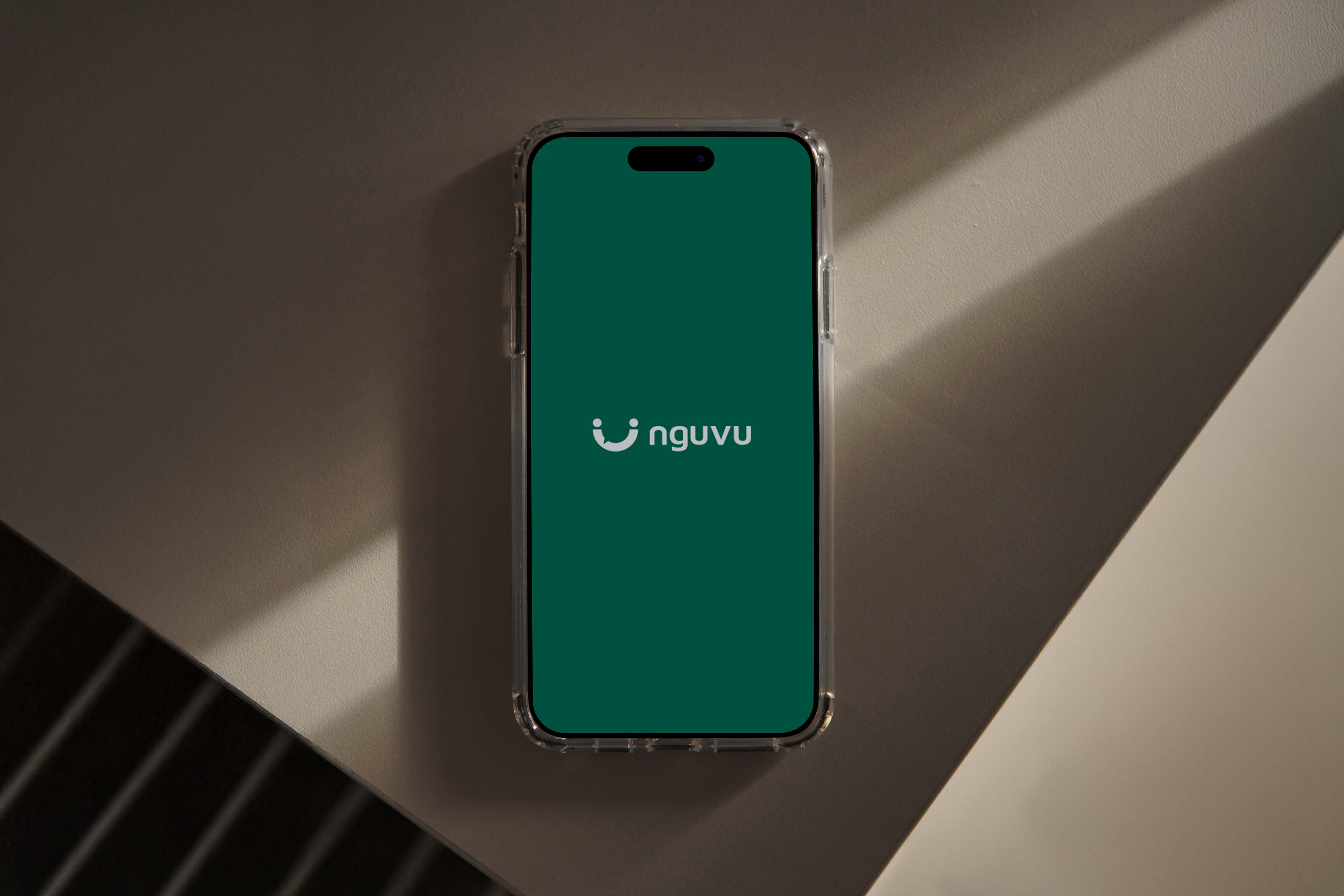 A smartphone displaying a green screen with a white logo in the center rests on a geometric gray surface, showcasing a modern mobile UI design.