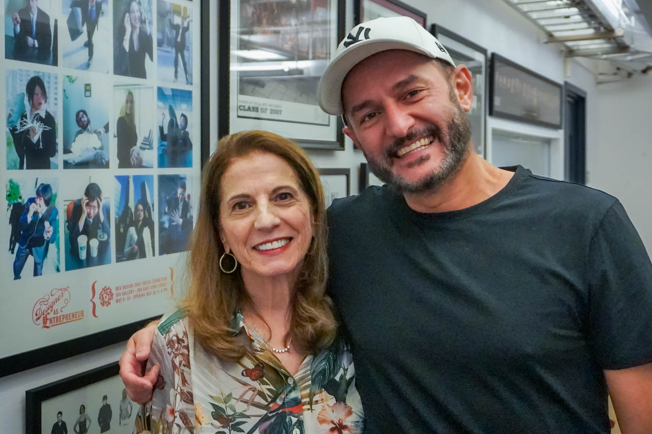 a man and a woman posing in front of a wall of photos