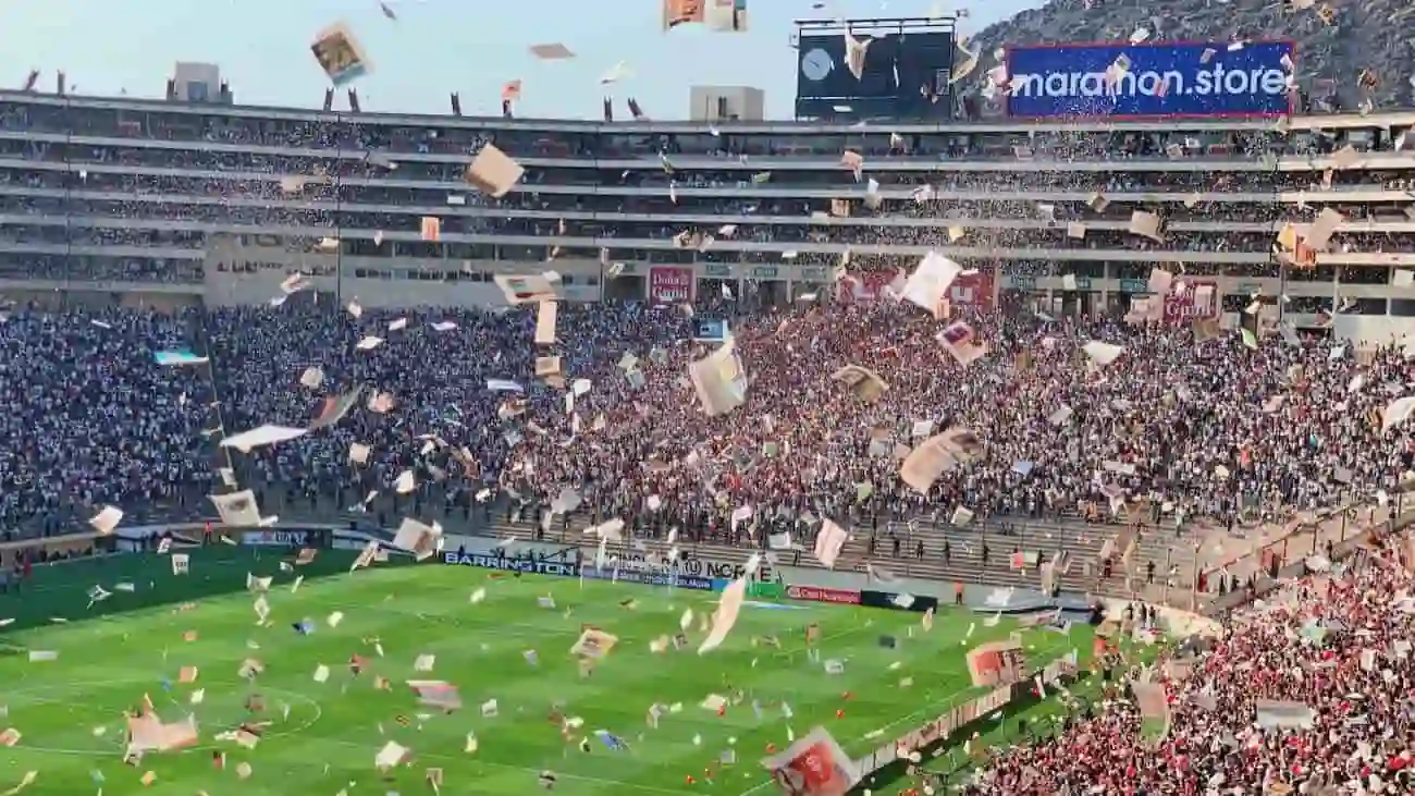 A packed football stadium with fans enthusiastically celebrating and throwing confetti during a match. The crowd's energy and the colourful confetti create a vibrant and festive atmosphere, highlighting the excitement and unity that well-organised football tournaments can bring. The image captures the passion of football fans and the electrifying ambiance that amplifies the sport's global appeal.