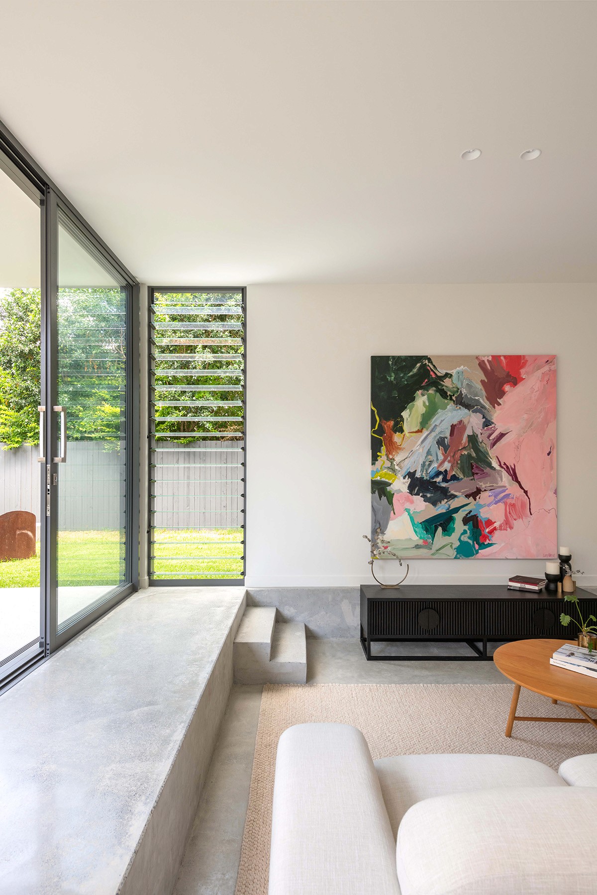 Living area at The Stables opening onto the courtyard, with built-in seating, operable glazing, and soft daylight shaping the interior.