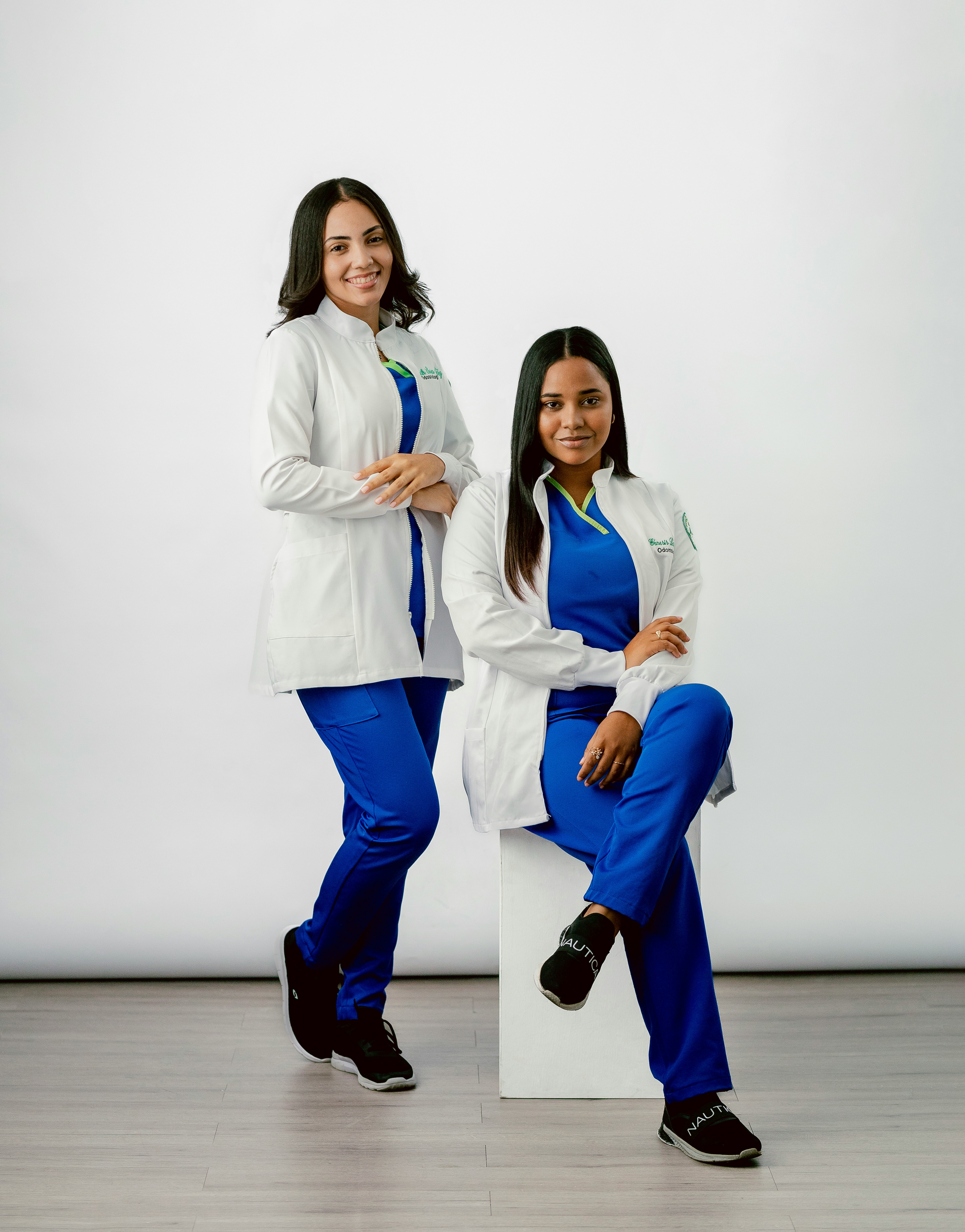 Two women are posing for a picture in front of a white background