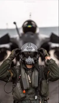 Fighter pilot in flight gear standing in front of a jet