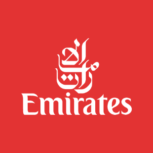 A young man with light brown hair is wearing a black suit jacket and white shirt, standing in a softly lit office setting, conveying professionalism.