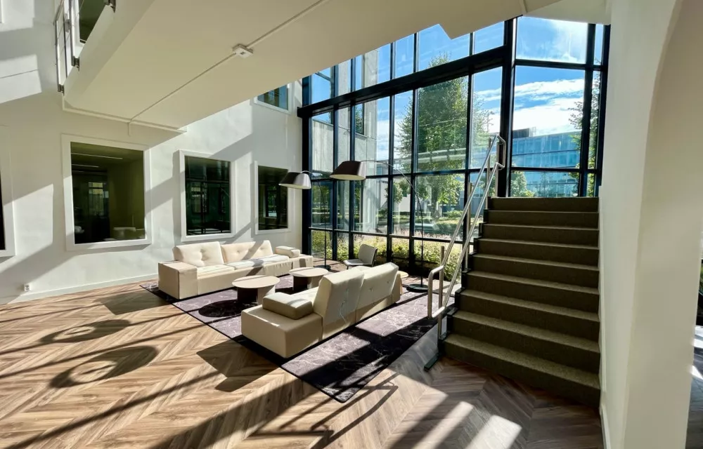 Ondernemers in gesprek aan tafel in een moderne kantoorruimte met zonlicht – Voco Finance contactmomenten