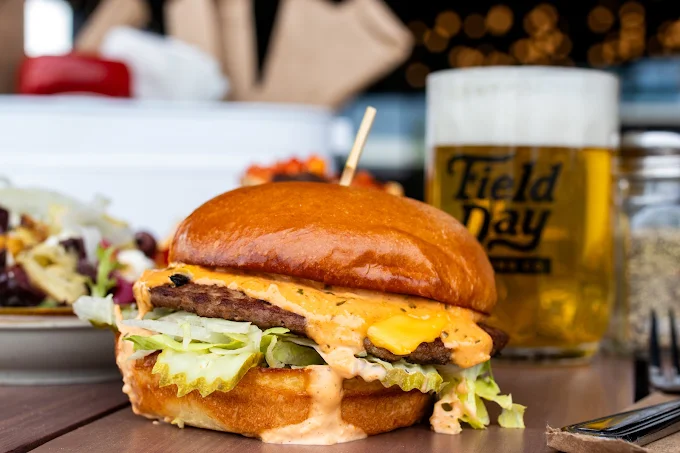 a burger with pickles, cheese, and a brioche bun