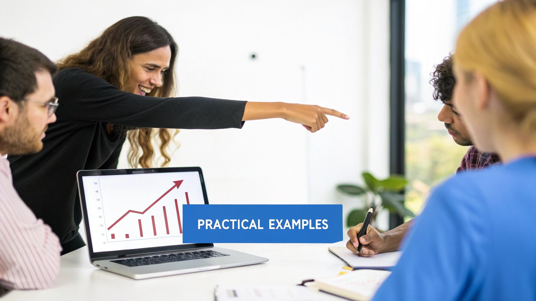 Smiling woman pointing during a business meeting with colleagues, a laptop showing a growth chart.
