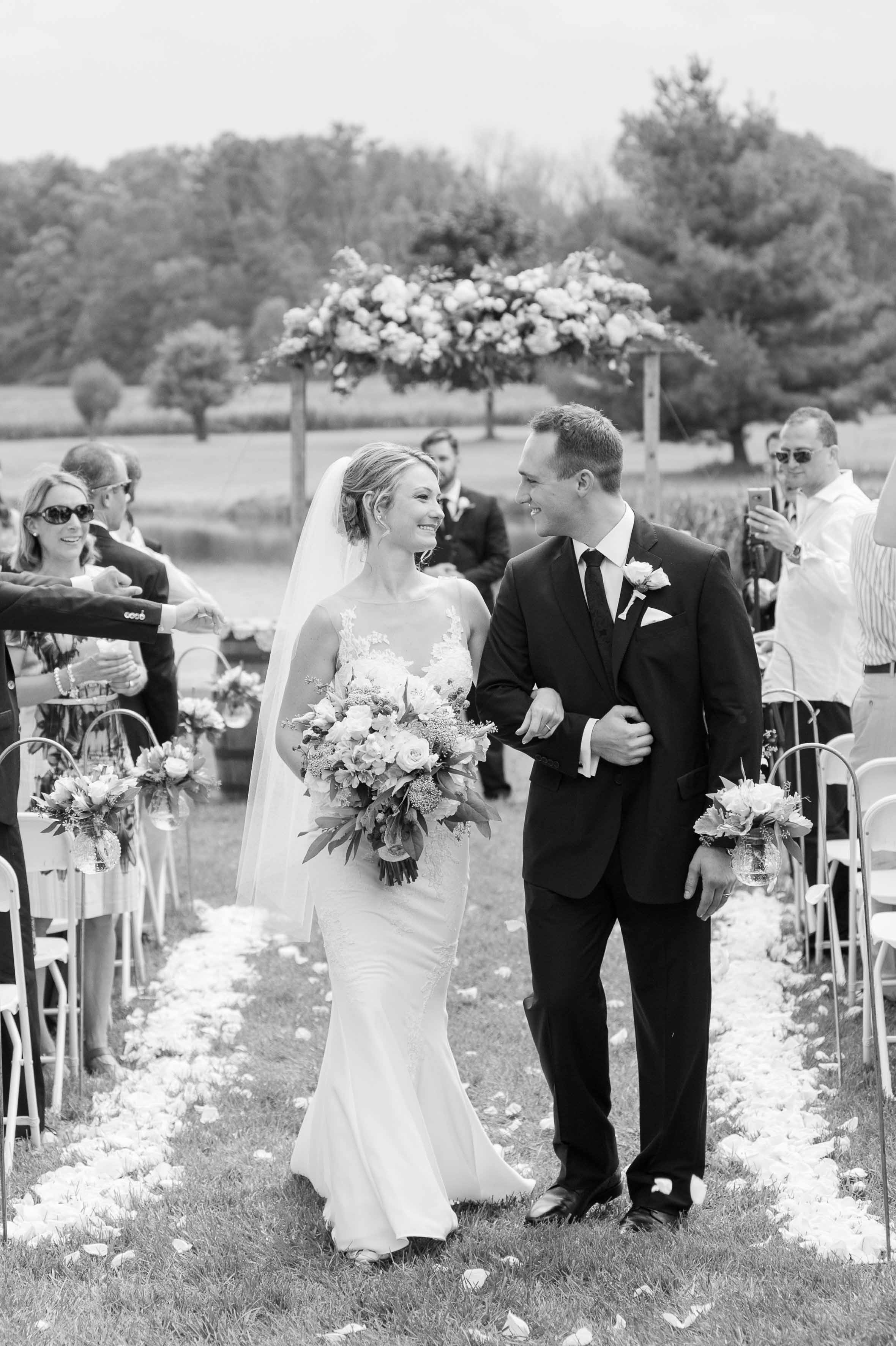 Black and white photo of couple walking down the aisle after just being married.