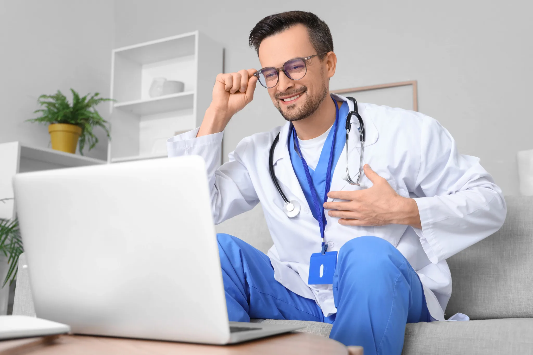 A caucasian male doctor sitting in front of laptop on a video call.