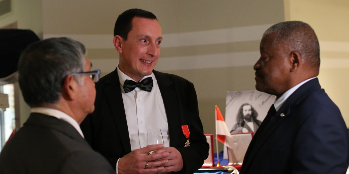 Prince Antoine V interacts with dignitaries at an event, wearing a tuxedo with a medal, promoting Mapuche advocacy.
