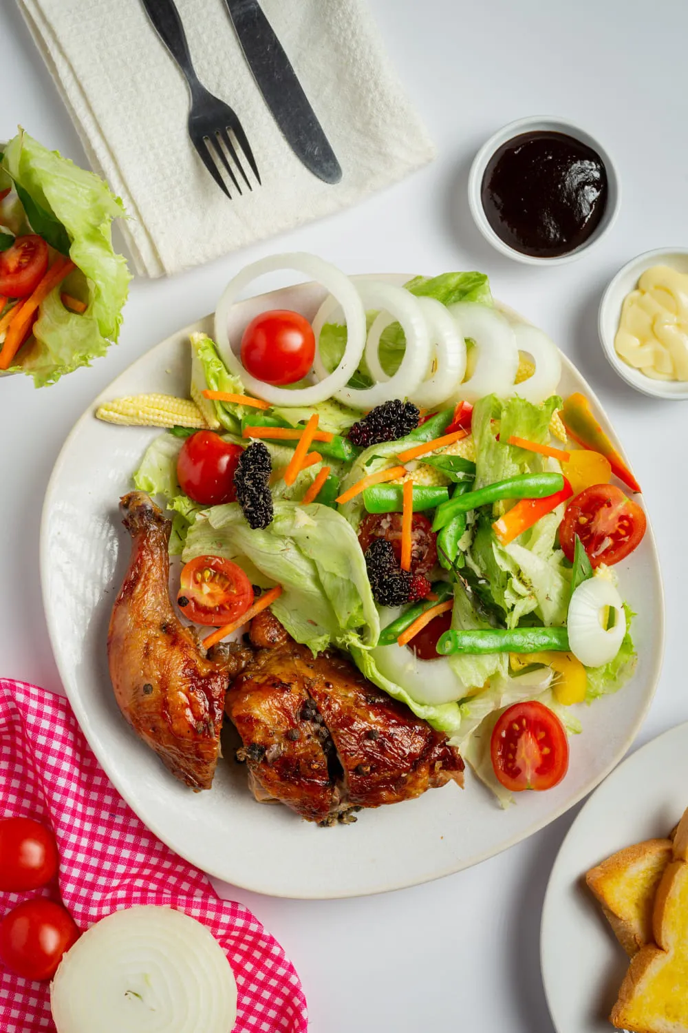 Roasted chicken with a colorful fresh salad on a white plate.