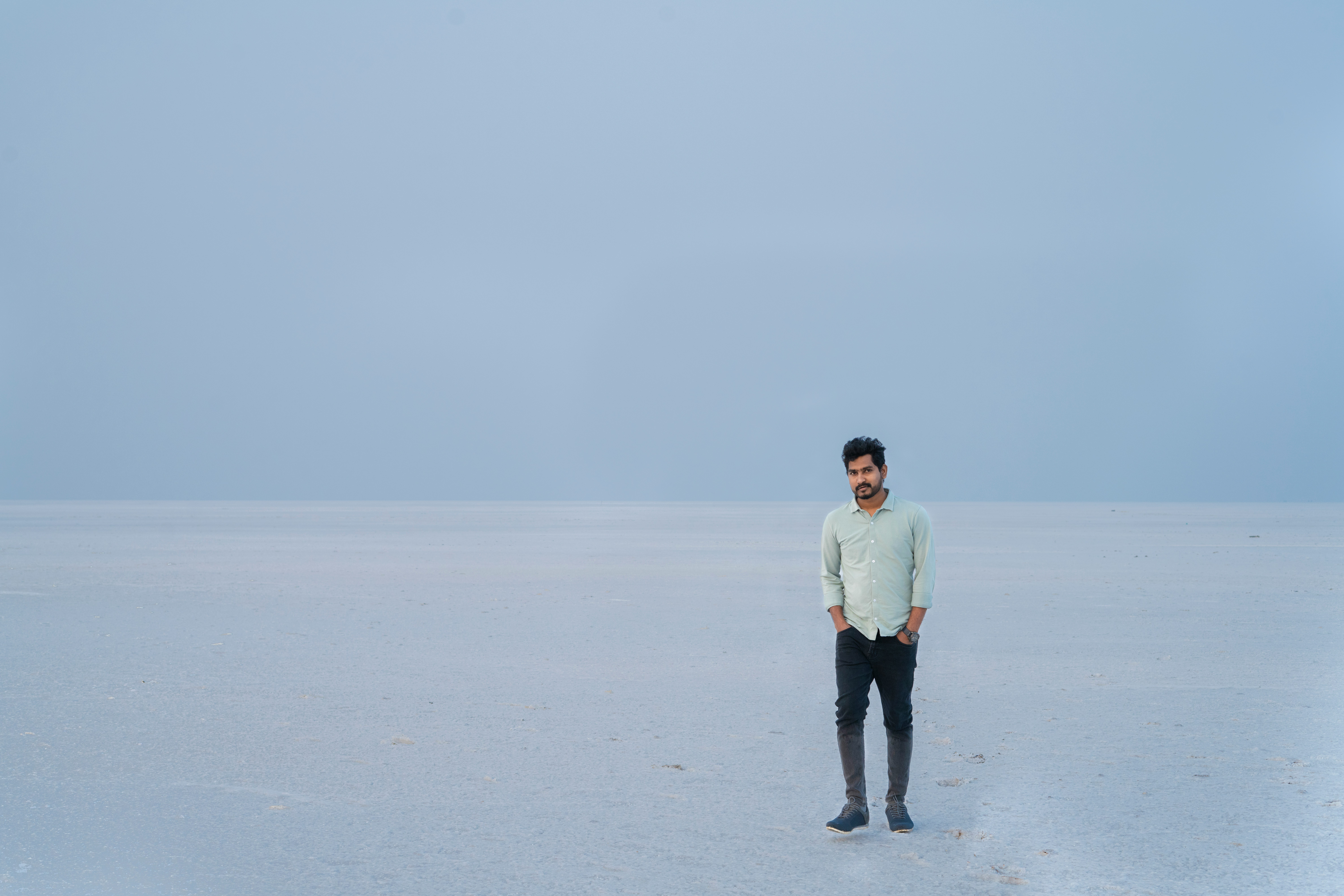 man in white dress shirt and black pants standing on white snow field during daytime