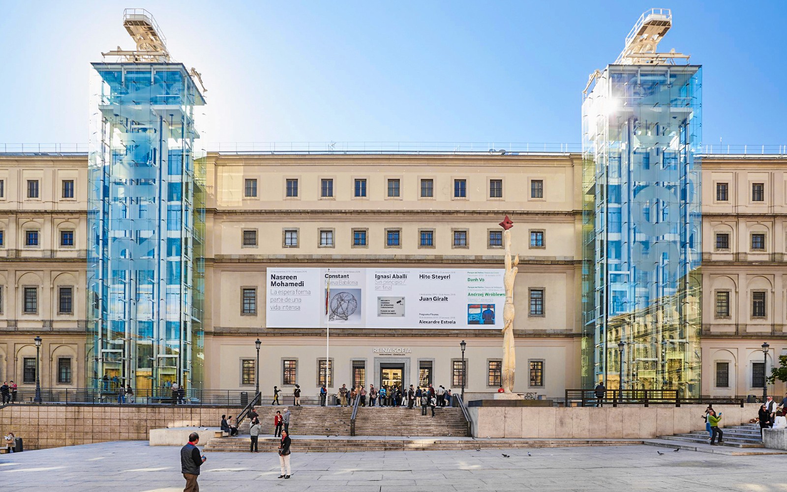 Reina Sofia Museum entrance with glass elevators and visitors in Madrid, Spain.