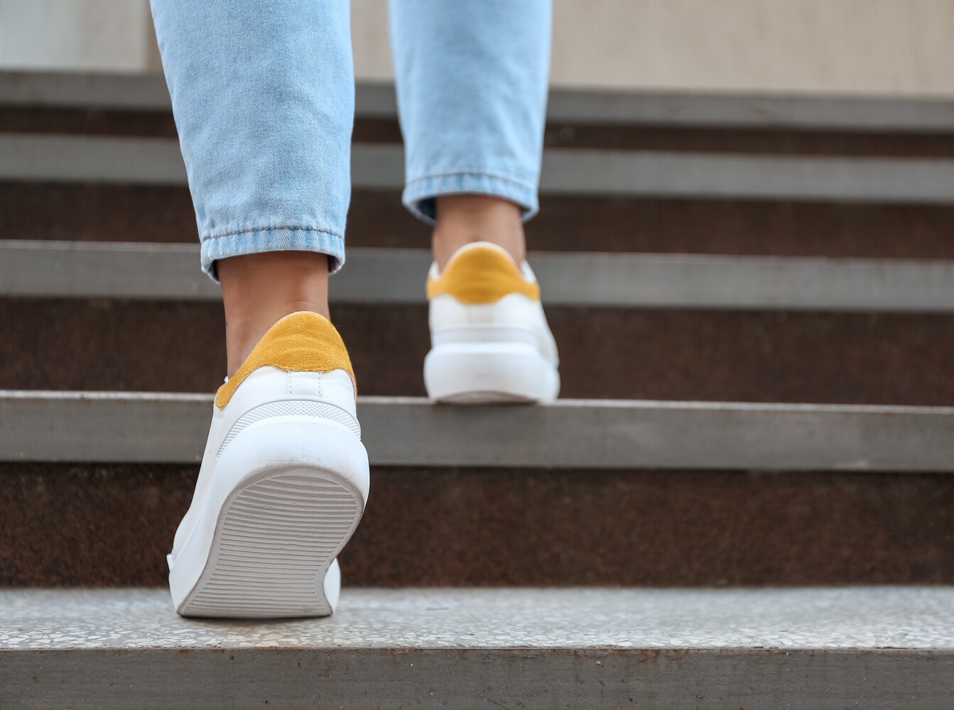 closeup of a woman walking up a set of stairs for NEAT in between her beginner workout routine for weight loss