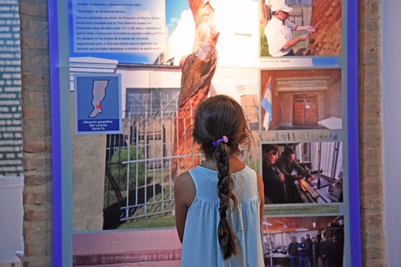 Black and white photo of two people looking at a computer screen with papers on wall