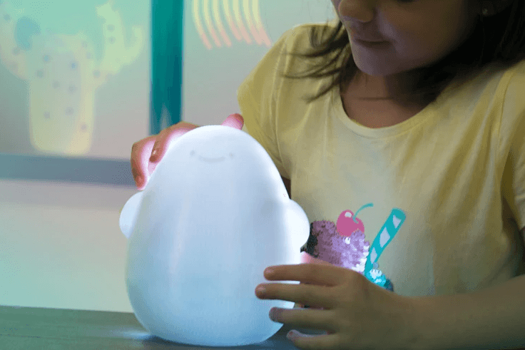 Young child holding the Globulus companion device, a soft rounded object with glowing light elements, in a hospital setting