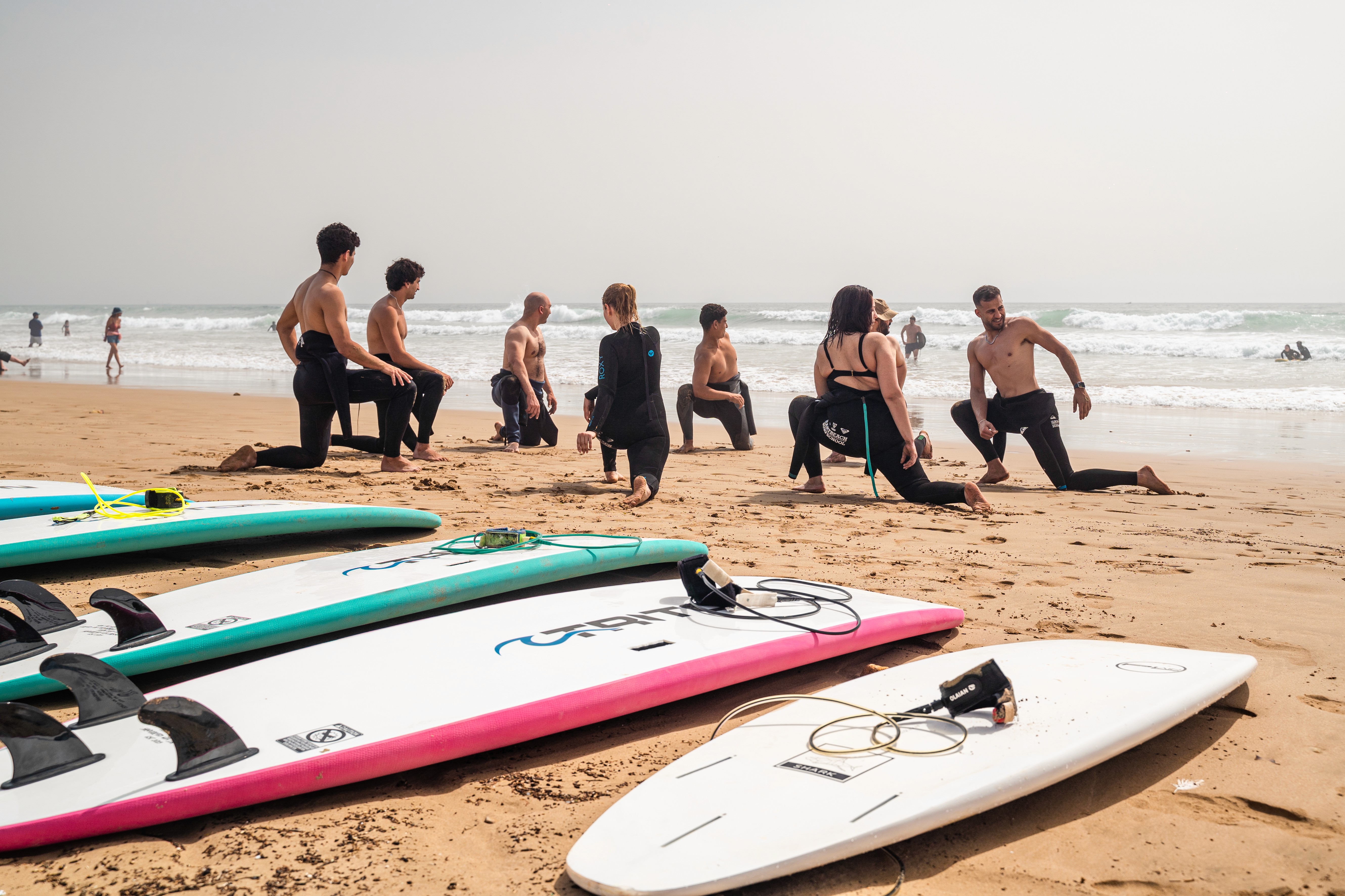 a group of people carrying surfboards on top of a beach