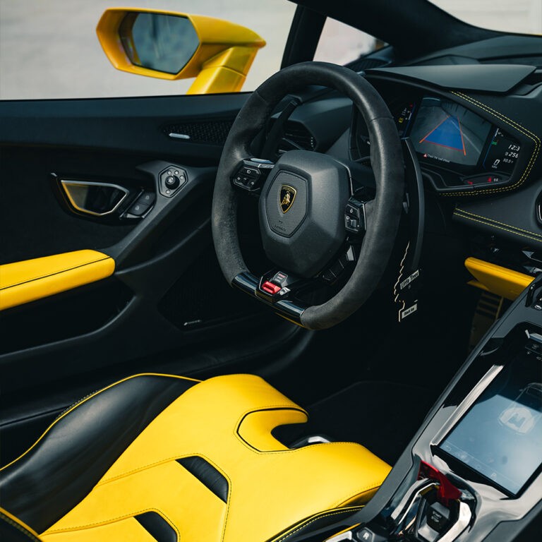 Driver's cockpit of yellow Lamborghini Huracán EVO Spyder, vibrant yellow and black interior, supercar rental Miami.