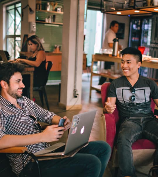 Two men are sitting on a chair and enjoying the conversation and smiling.