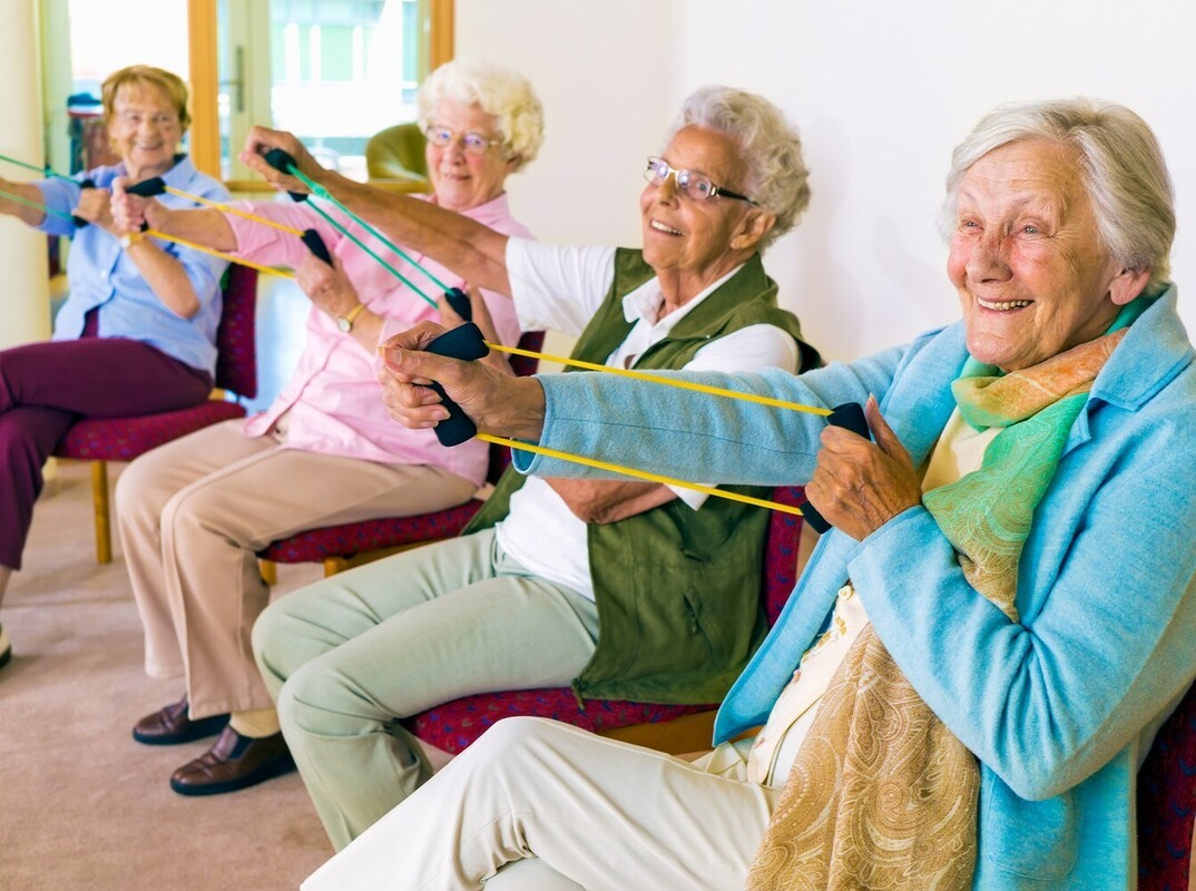 group of senior women doing a fun class for seated exercises to lose belly fat using resistance bands